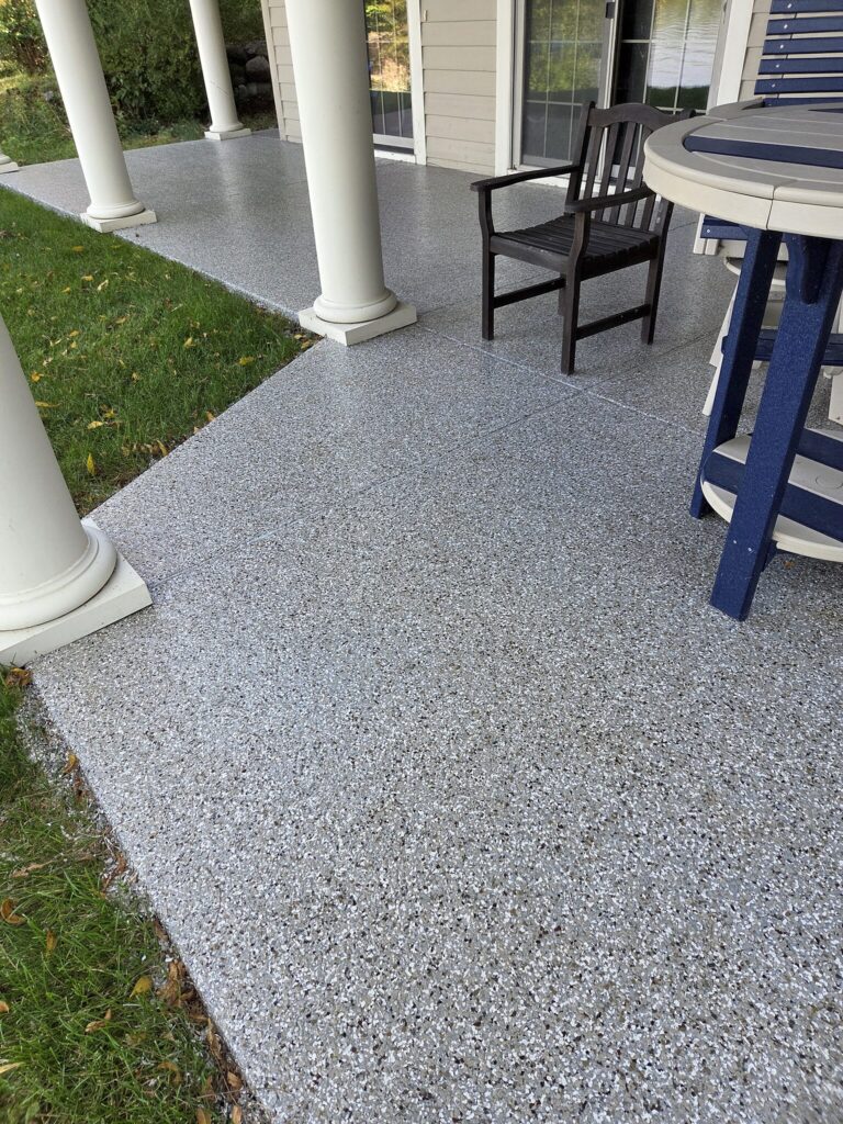 Gray flake-coated covered porch with white columns in Oconomowoc