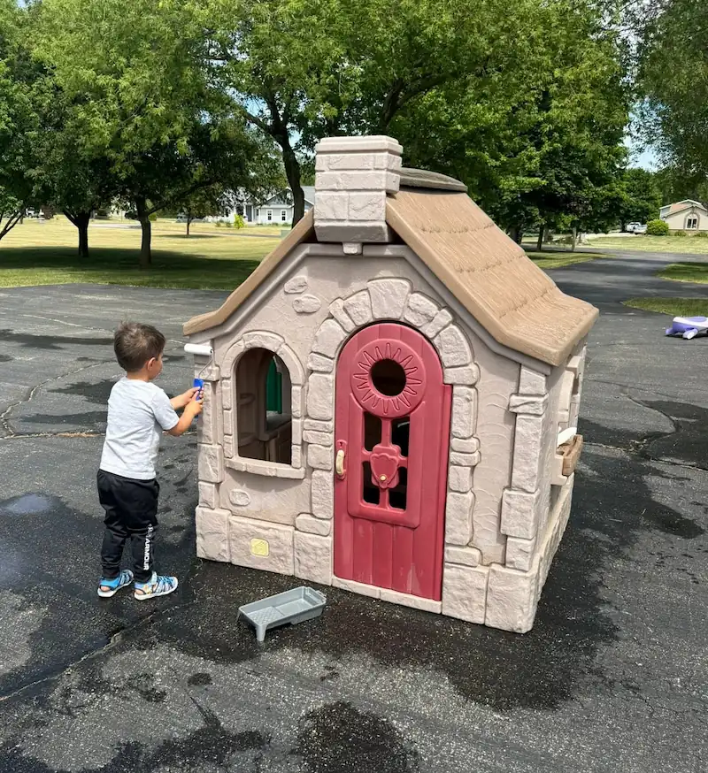 Chad's son painting a playhouse with a roller