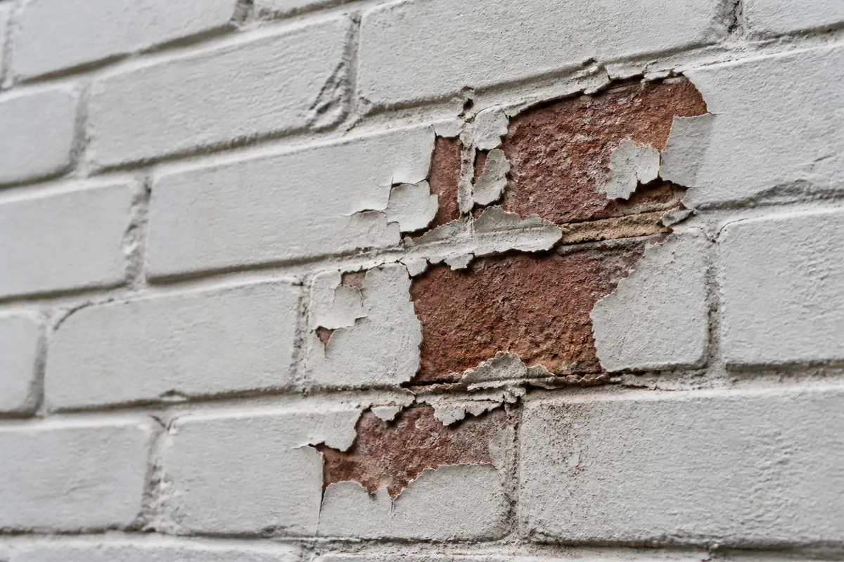 Illustration of peeling coating exposing red brick beneath