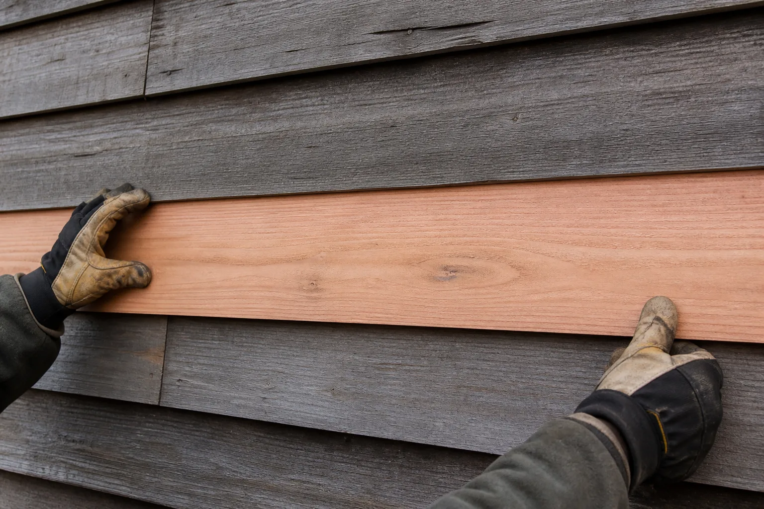 Contractor installing a full-length replacement cedar lap siding board