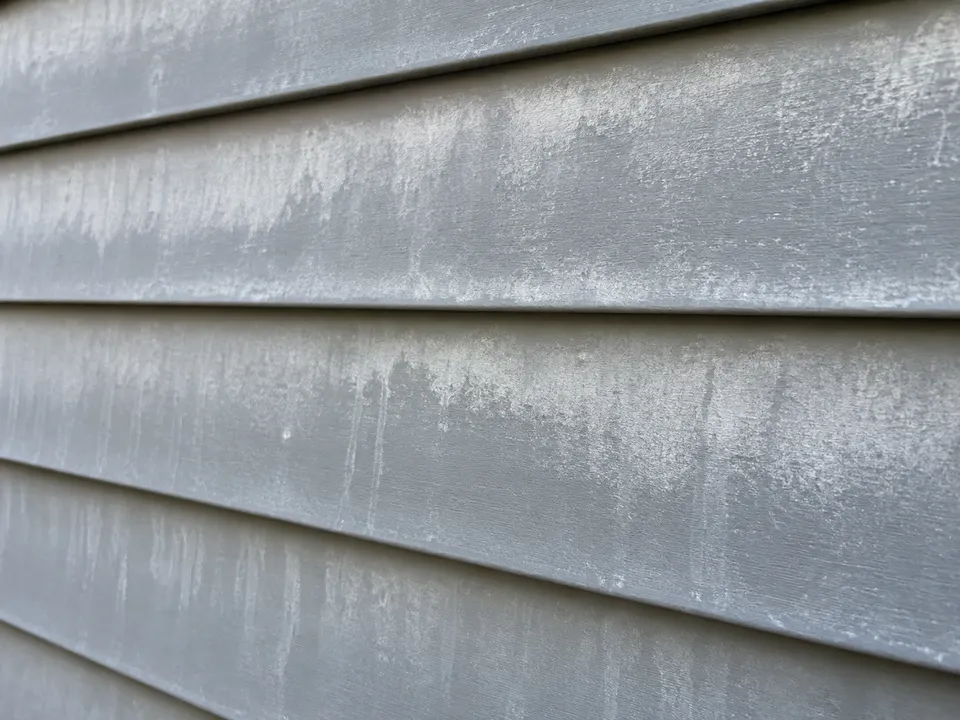 Powdery chalk and oxidation residue across weathered aluminum siding