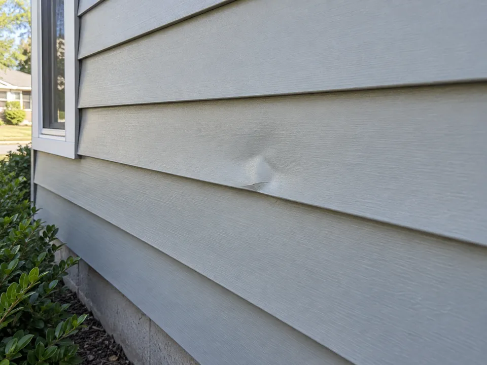 Shallow localized dent in an otherwise aligned aluminum siding panel
