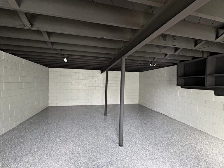 Basement with a black-painted joist ceiling and gray flake floor in North Prairie