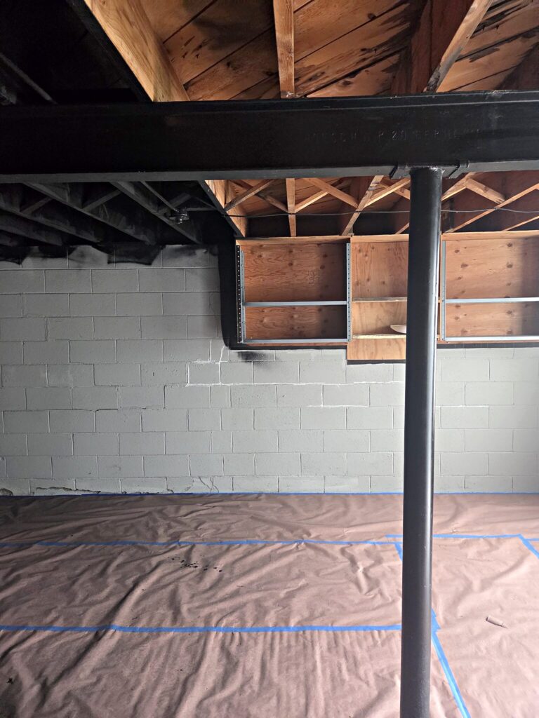 Open wood-joist ceiling painted dark in an Eagle basement