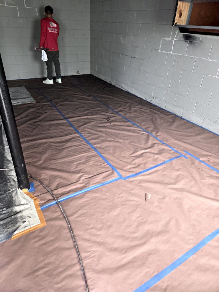 Basement floor covered with paper and tape before painting in Eagle