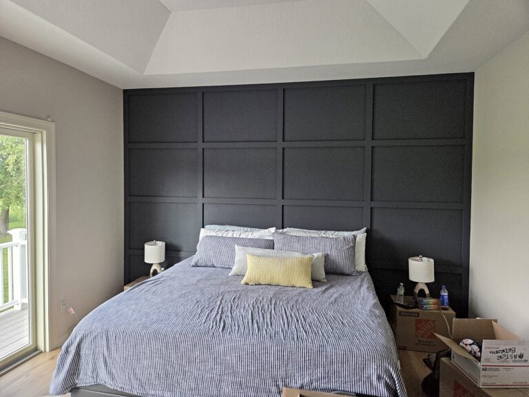 Bedroom with a dark-painted paneled accent wall in North Prairie