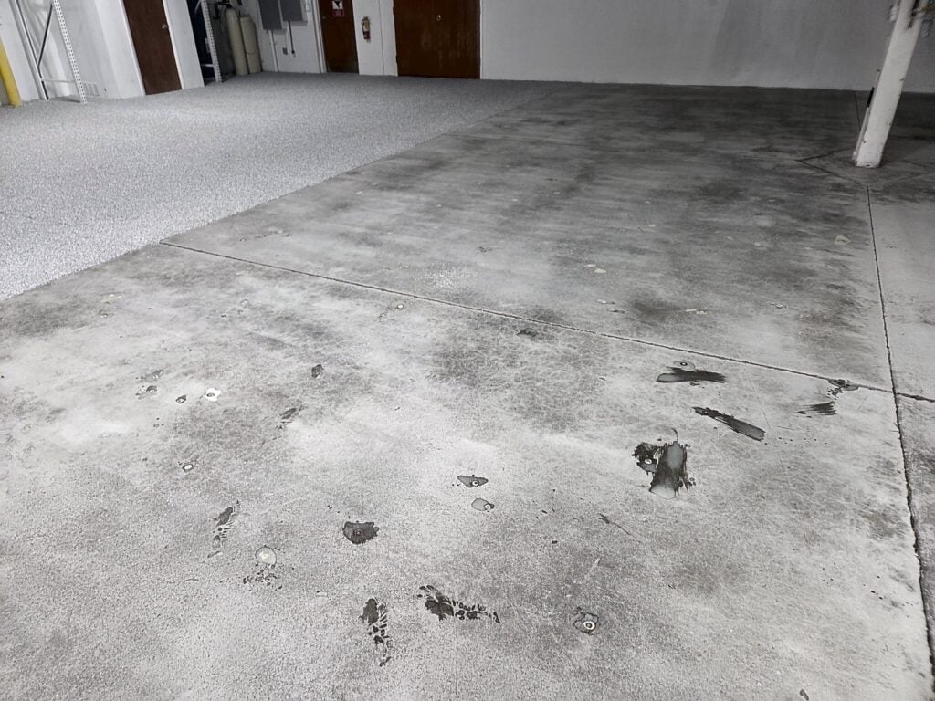 Bare concrete shop floor with dark stains before preparation in New Berlin