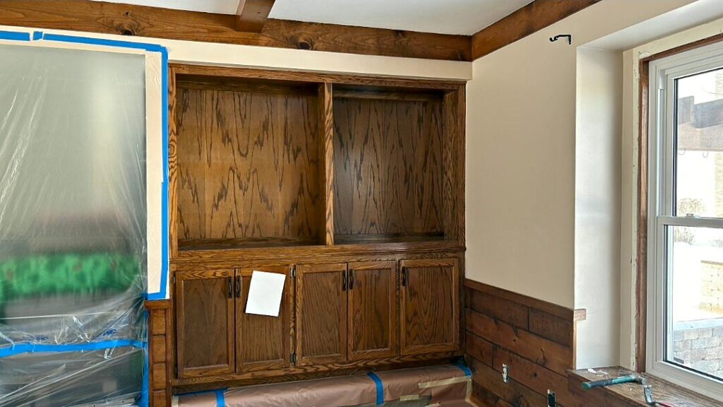 Stained wood built-ins and paneling masked with plastic before painting in Waukesha