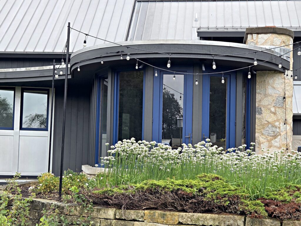 Windows taped and masked on a dark-sided house with stone details in Mukwonago