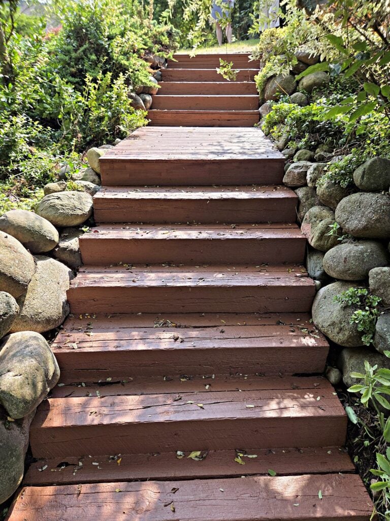 Wooden outdoor stairs between boulders finished with a solid stain in Waukesha