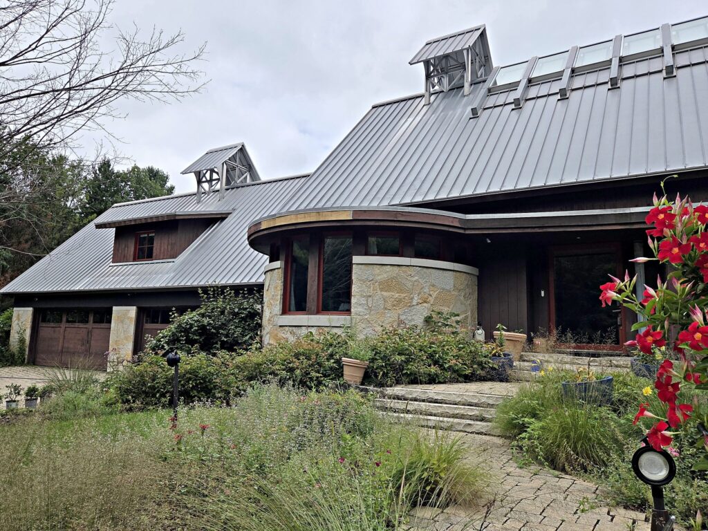 Dark-stained house with a stone tower and gray metal roof in Mukwonago